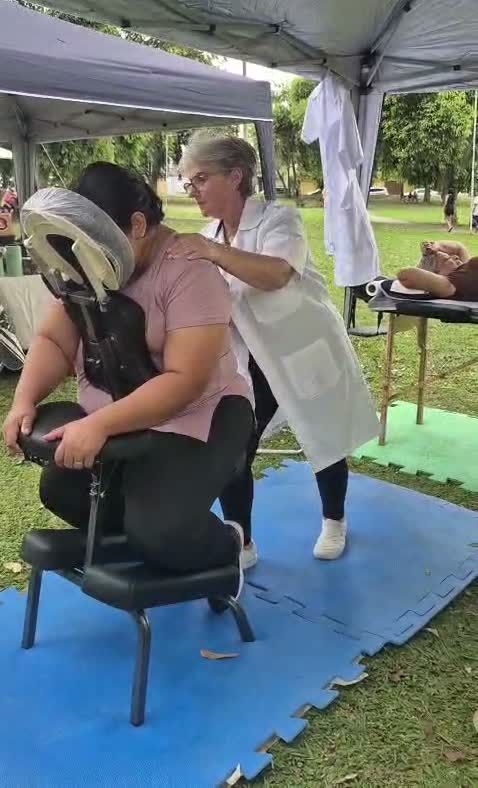 Célia atendendo uma cliente na cadeira de quick massage, durante um evento na praça